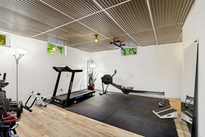 Corrugated metal ceiling with grid system, wood-finish flooring, recessed windows, and white walls