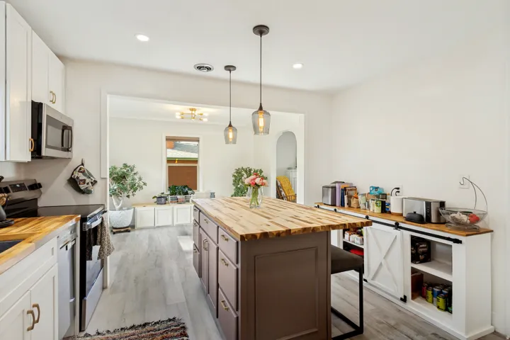 Kitchen with wood-finish countertops, stainless steel appliances, and an island featuring pendant lighting