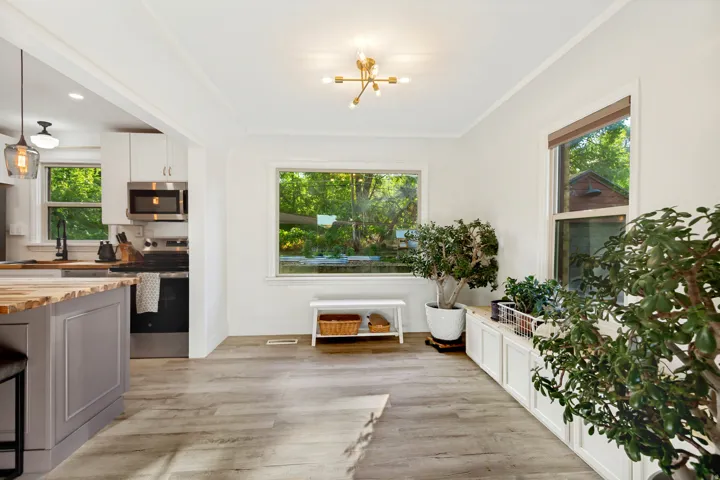 Open-concept space featuring wood-finish flooring, a modern brass light fixture, and built-in white cabinetry