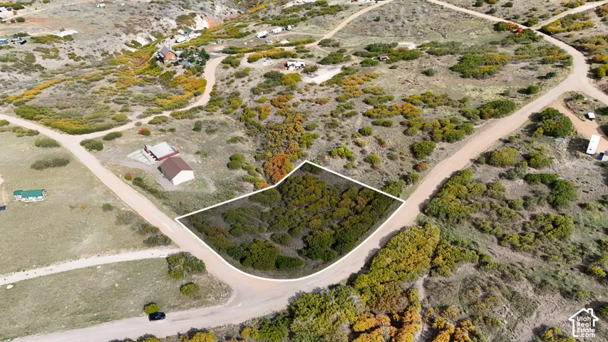 Aerial perspective of a corner lot featuring native vegetation, topographical variation, and direct access to unpaved roads