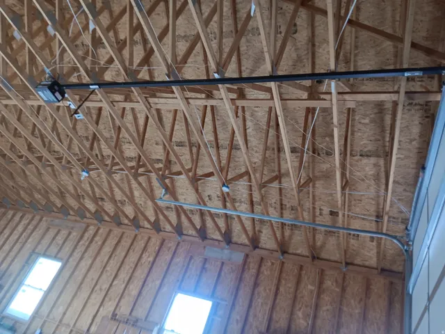 Exposed wood ceiling joists and subflooring with mechanical garage door opener