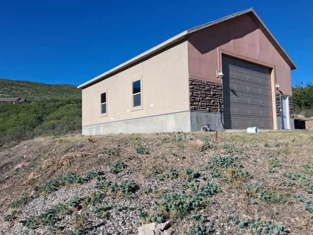 Detached structure with stucco siding, a stone accent facade, a large garage door, and two side windows