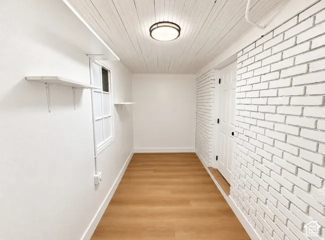 Wood-finish flooring with white brick accent wall
