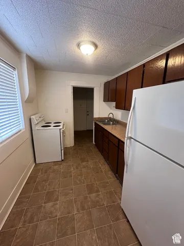 Kitchen featuring tile flooring, white appliances, brown wood-finish cabinetry, and laminate countertops