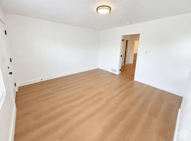 Wood-finish flooring, white walls, and a contemporary flush-mount ceiling light