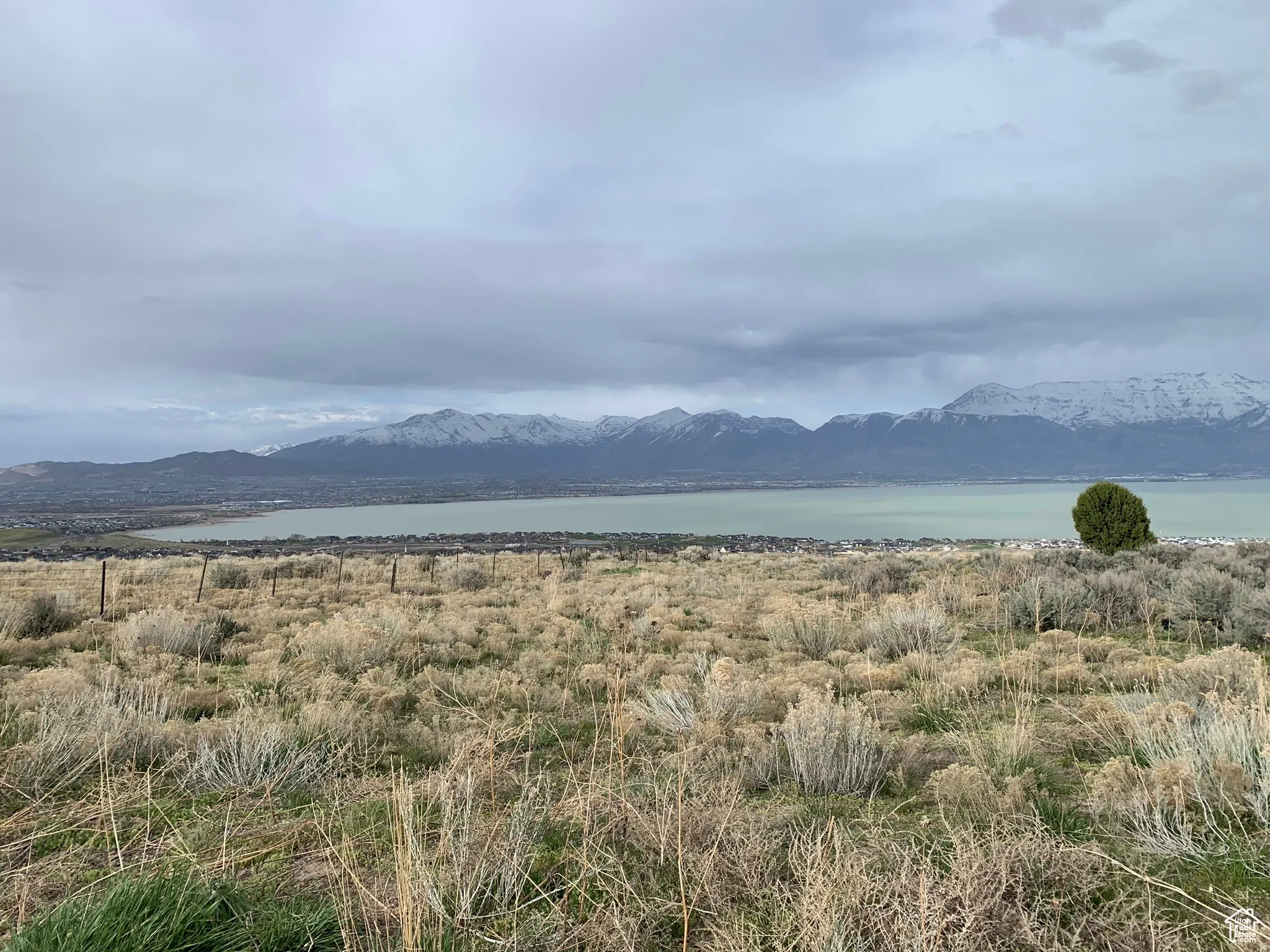 Expansive open landscape featuring a distant body of water and snow-capped mountain range