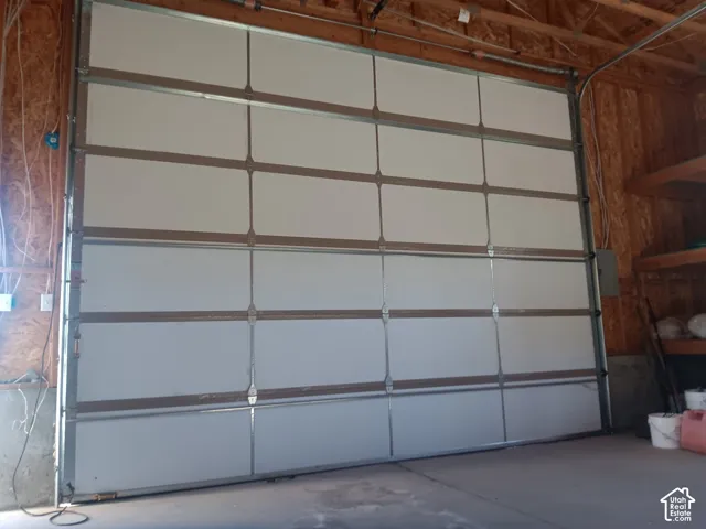 Insulated sectional garage door with metal frame construction, featuring exposed timber wall studs and built-in shelving