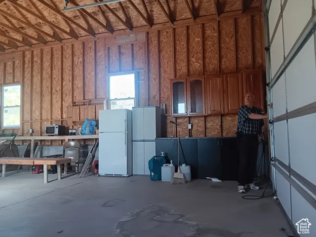 Garage featuring exposed structural wood framing, concrete flooring, dual windows, and built-in wall-mounted cabinetry