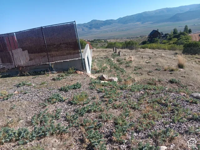 Expansive hillside lot featuring a concrete foundation, metal privacy fencing, and mountain terrain
