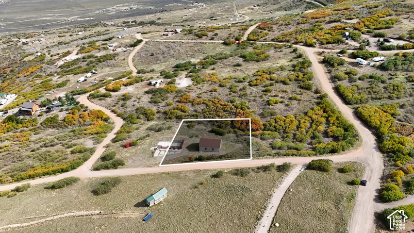 Expansive hillside lot featuring native shrubbery, mature trees, and a detached structure with a pitched metal roof