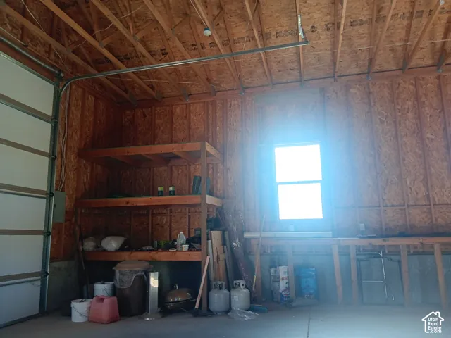 Garage interior featuring exposed wood-stud construction, built-in wooden shelving, and a single-hung window