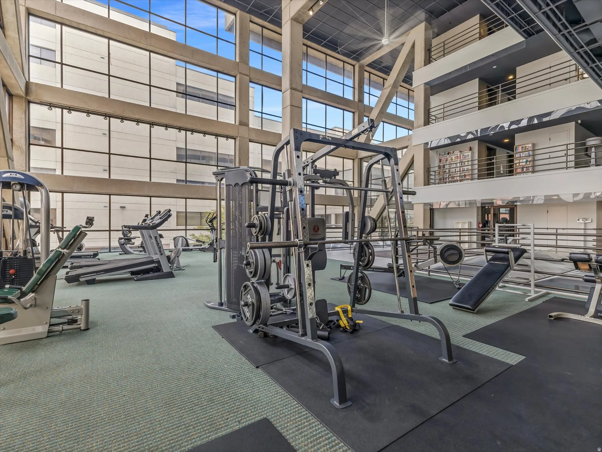 Fitness center featuring large floor-to-ceiling windows, extensive exercise equipment, carpeted and rubber flooring, and an open-concept multi-level design