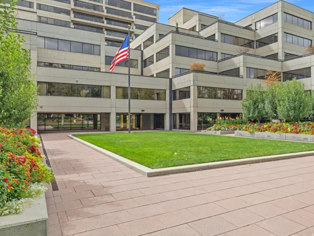 Modern building exterior featuring a landscaped lawn area, paver pathway, and multiple raised garden beds