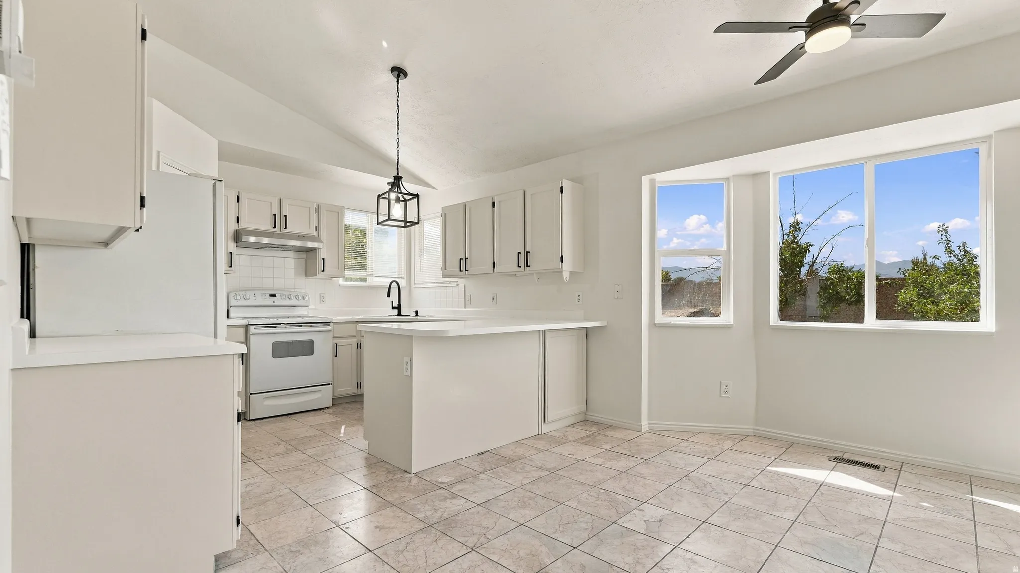 Kitchen featuring white cabinetry, tile flooring, a central island, and a geometric pendant light fixture