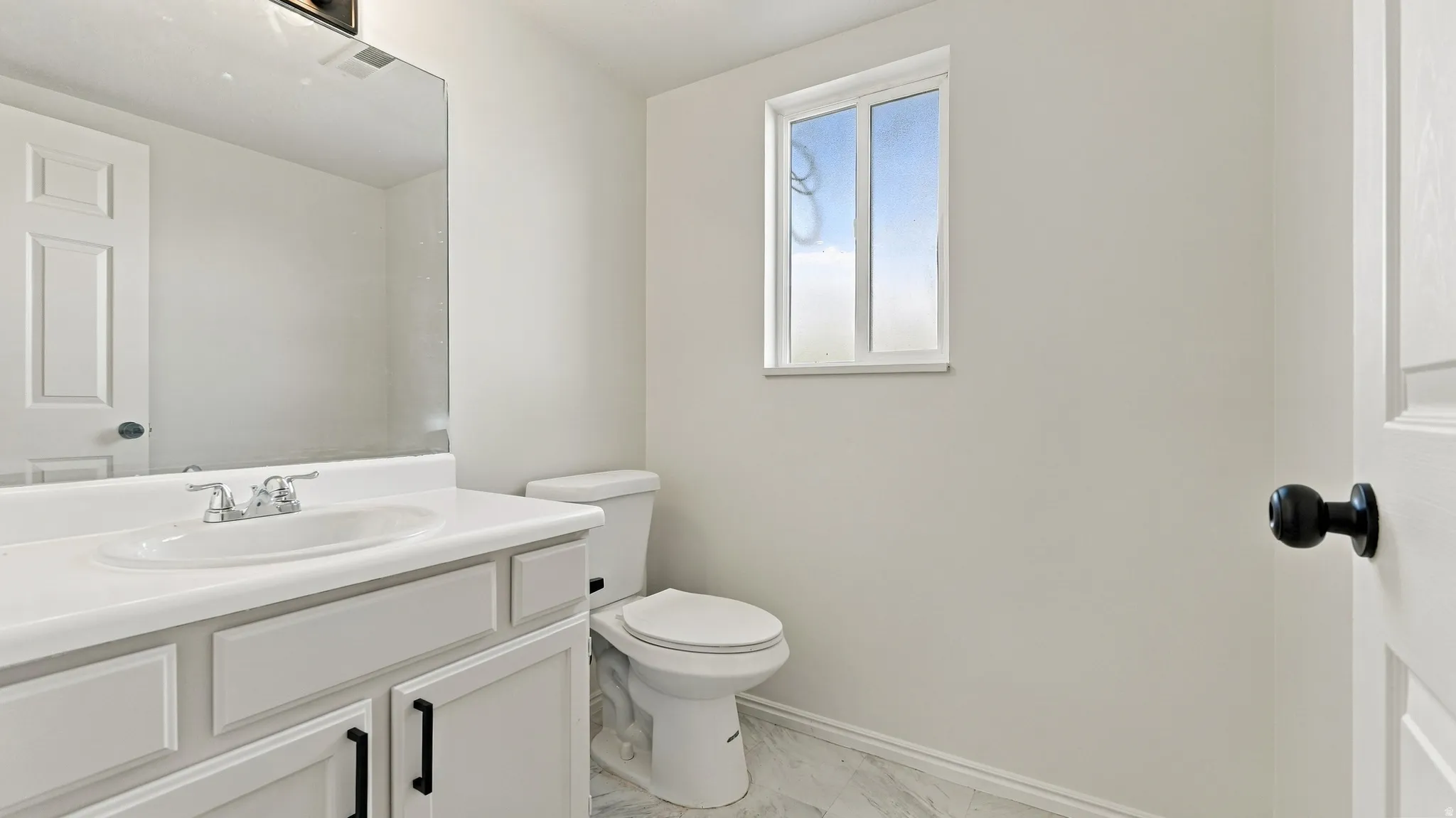 White shaker-style vanity with a white countertop and undermount sink