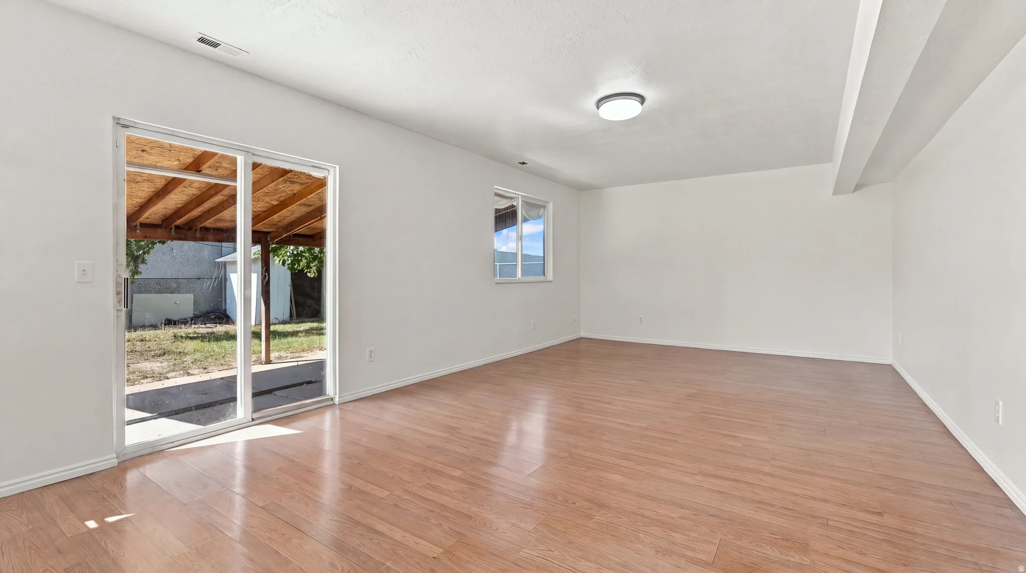 Expansive room with wood-finish flooring, white walls, and a recessed ceiling light