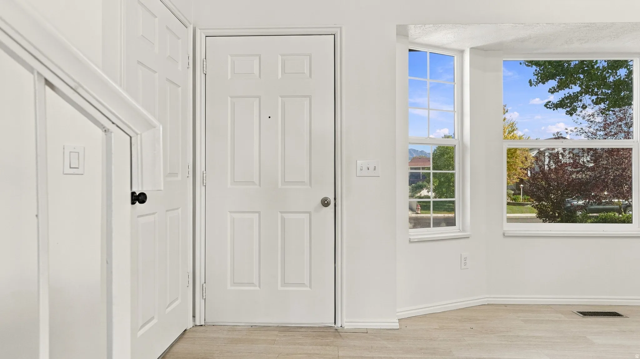 Entryway featuring a paneled door, wood-finish flooring, and bay windows