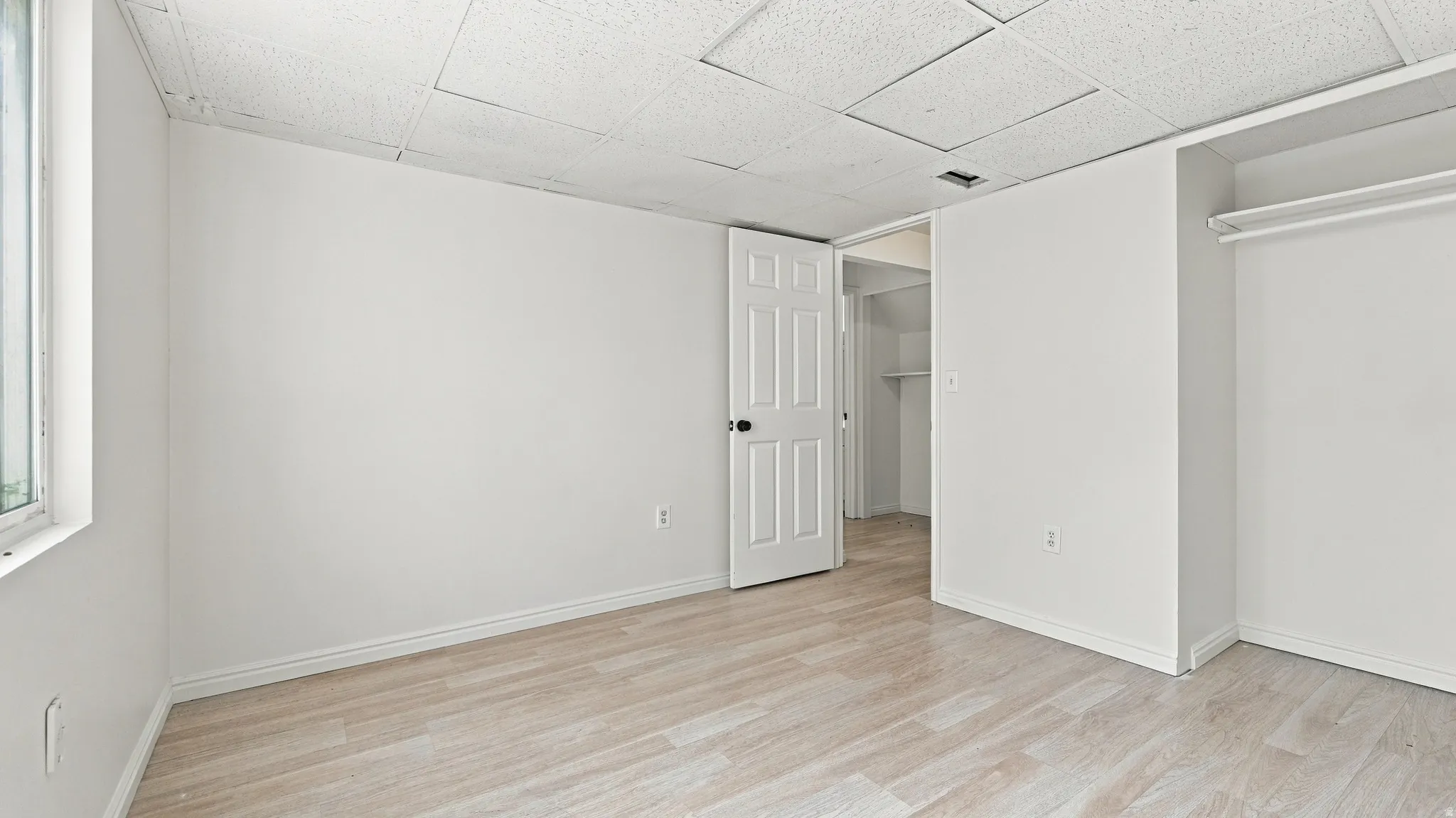 Recessed closet space with hanging rod, wood-finish flooring, and white paneled door