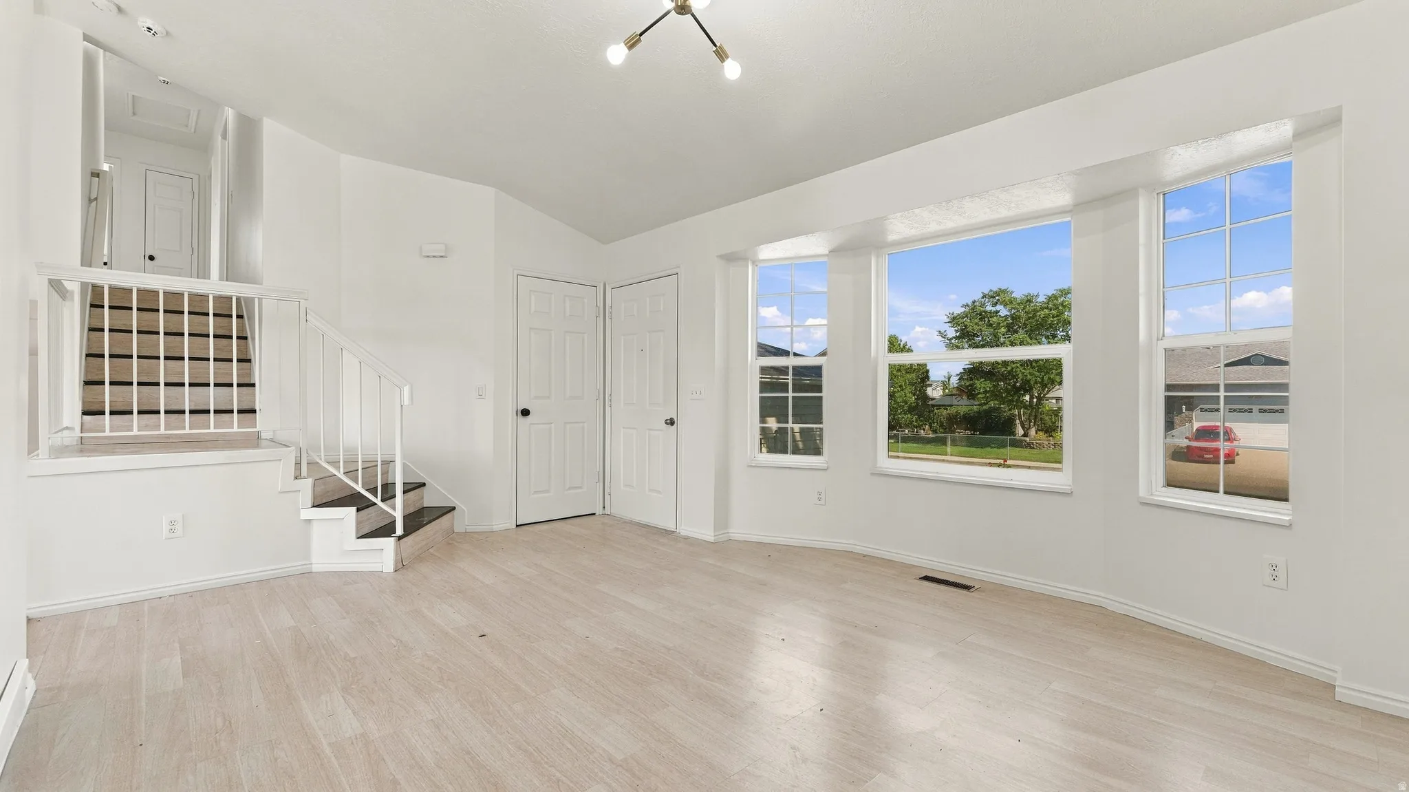 Light wood-finish flooring with a multi-pane bay window