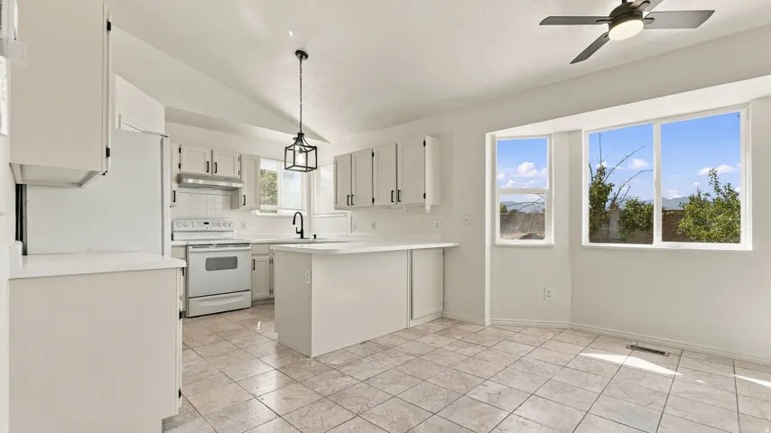 Kitchen featuring white cabinetry, tile flooring, a central island, and a geometric pendant light fixture