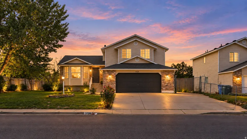 Two-story exterior with stone accents and siding, an attached two-car garage, and a concrete driveway