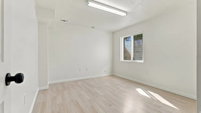 Light wood-finish flooring, white walls, and a window with a white frame