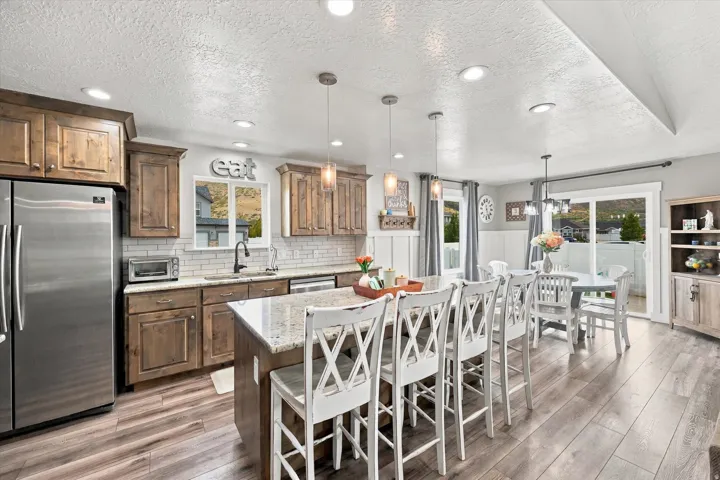 Kitchen featuring wood-finish cabinetry, stainless steel refrigerator, white subway tile backsplash, and recessed lighting
