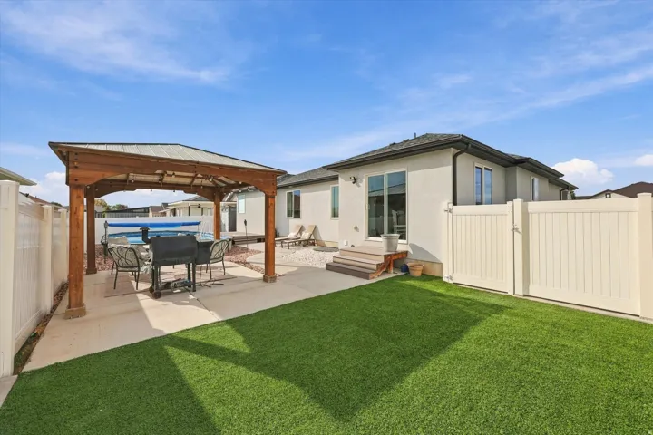 Expansive outdoor space featuring a wood pergola, concrete patio, artificial turf, and a private fence
