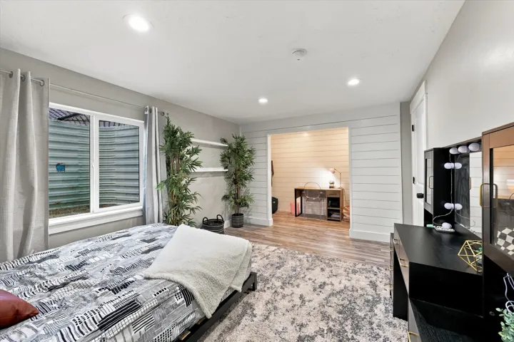 Recessed lighting illuminates the room, featuring a window with a well-designed window well, and a doorway opening to an additional space
