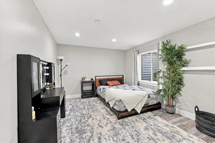 Recessed ceiling lighting, wood-finish flooring, and a large window with privacy blinds
