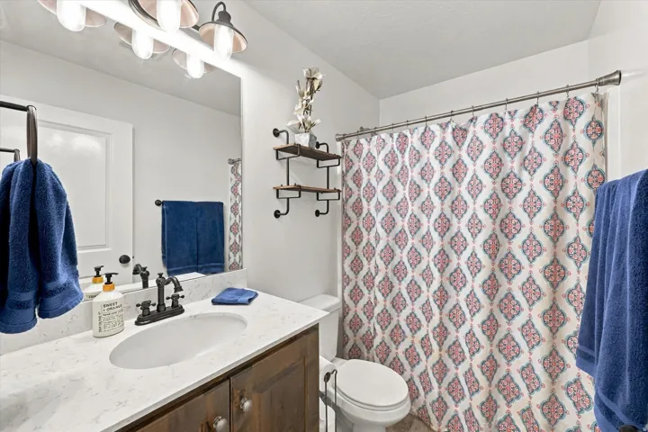 Vanity with integrated sink and dark wood-finish cabinetry, light-colored countertop, and a wall-mounted mirror