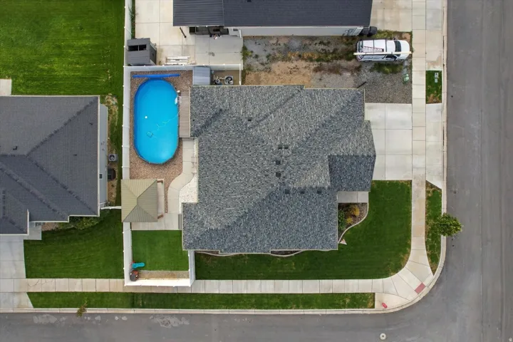 Exterior featuring an above-ground pool, covered patio, manicured lawn, and paved walkways