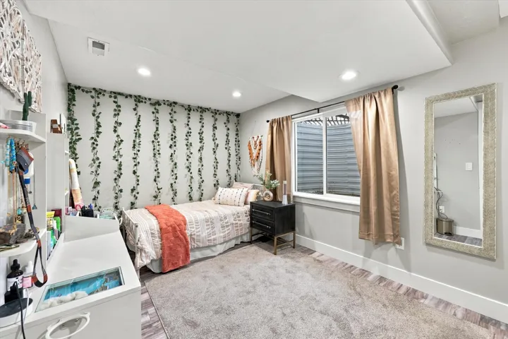 Recessed ceiling lighting, window with light-filtering curtains, carpeted flooring, and a decorative wall treatment