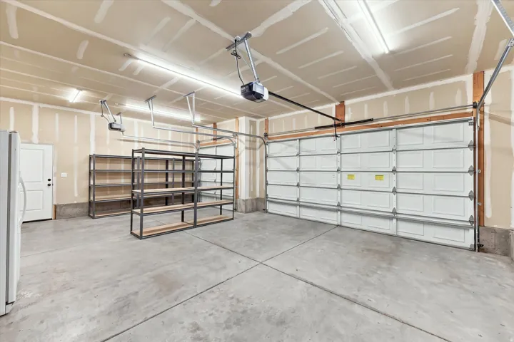 Expansive garage with concrete flooring, two automatic garage doors, and overhead lighting