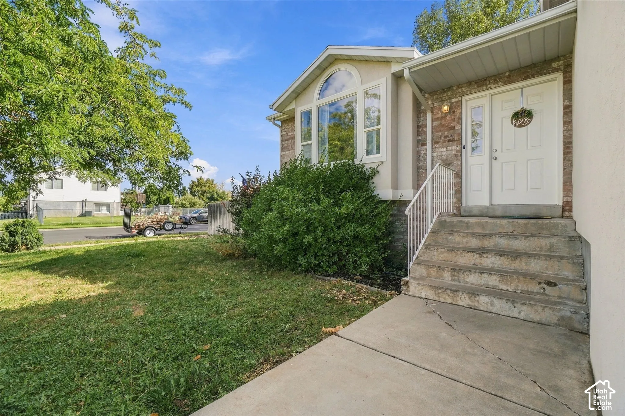 Brick facade with a prominent bay window, dual entry doors, and a concrete pathway leading to the entrance