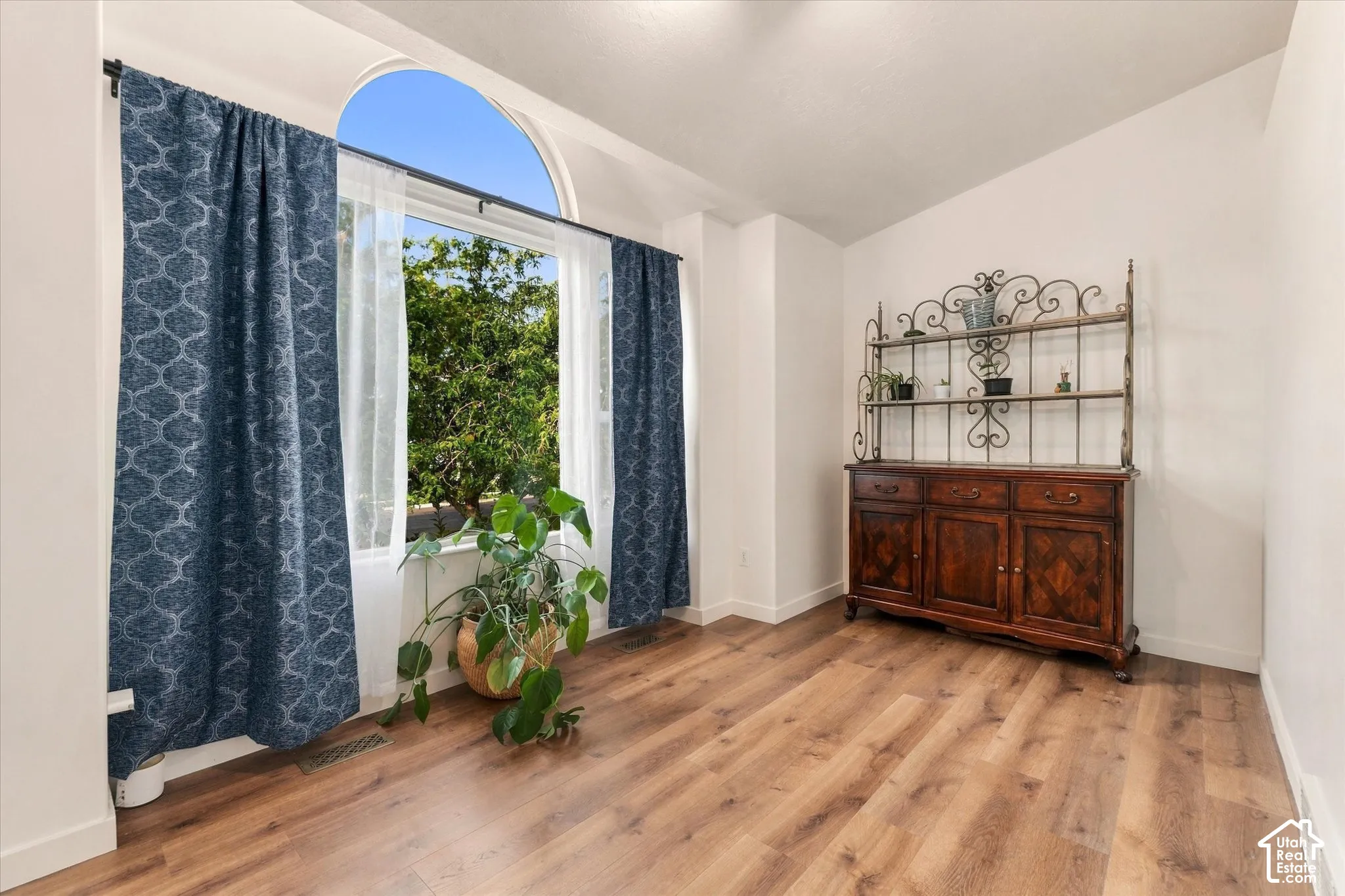 Wood-finish flooring with white baseboards, featuring a large window with an arched transom