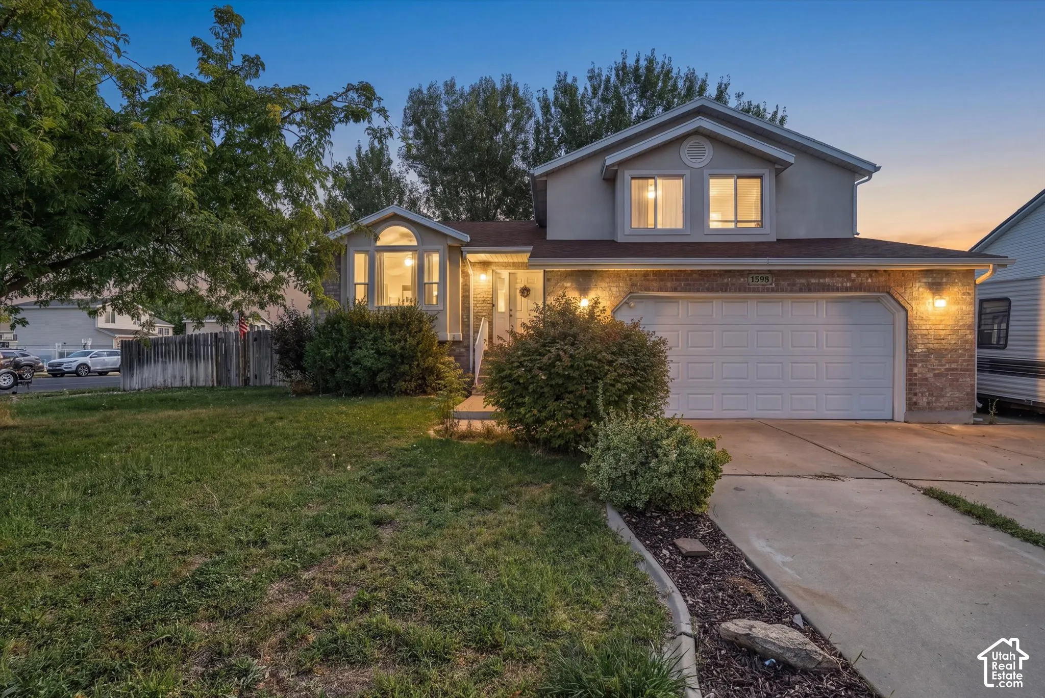 Brick and siding exterior with an attached garage, landscaped front yard, concrete driveway, and front entry stairs
