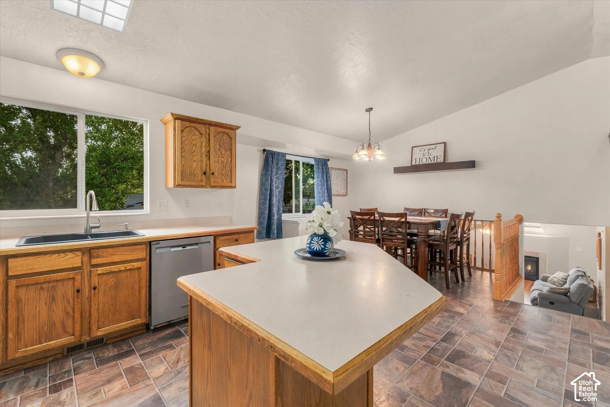 Kitchen with wood cabinetry, stainless steel dishwasher, and a large window