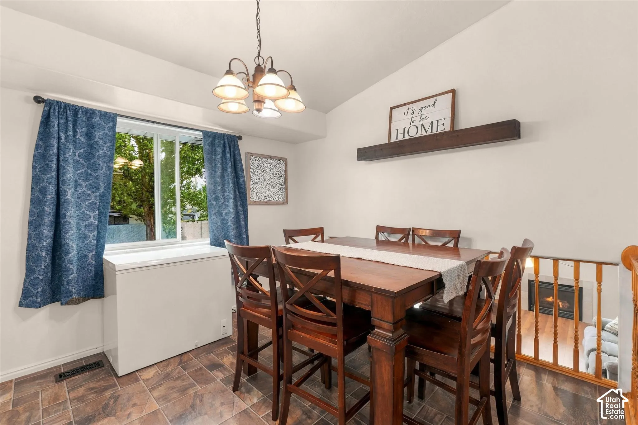 Vaulted ceiling with an overhead chandelier, window with ample natural light, and tiled flooring