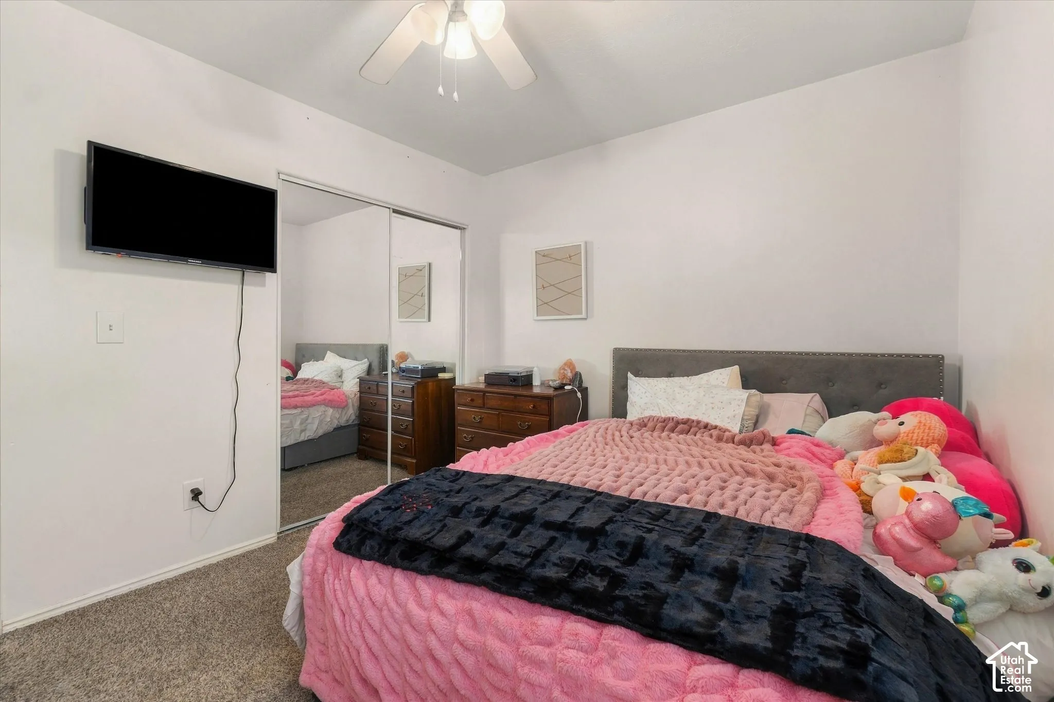 Ceiling fan with light fixture, mirrored closet doors, and carpet flooring