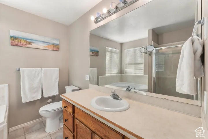 Bathroom featuring a wood-finish vanity with an integrated sink, a large wall-mounted mirror, a separate toilet area, and a built-in tub with privacy blinds