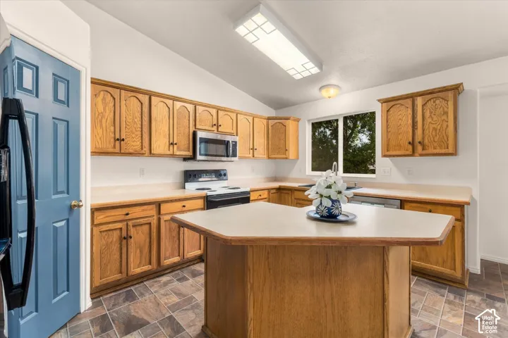 Kitchen featuring wood cabinetry, a center island with countertop, stainless steel microwave, and an electric range