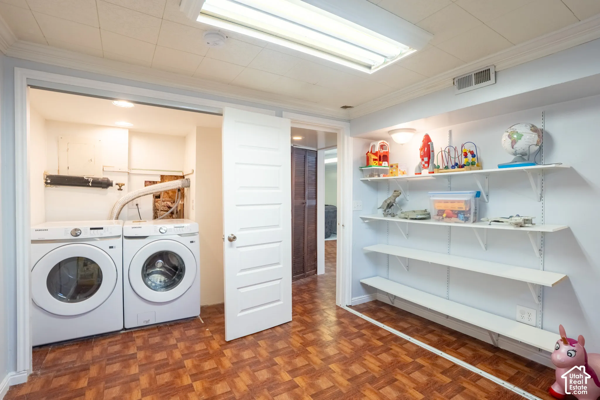 Laundry area with front-load washer and dryer, adjacent to built-in shelving, and wood-finish flooring, also Bedroom 5