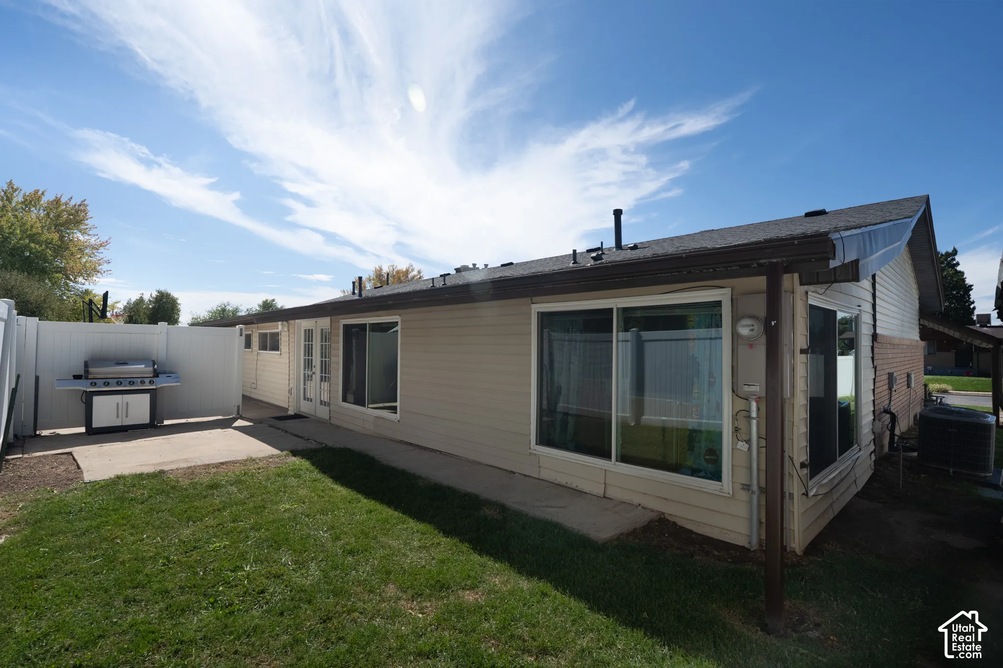 Backyard with a concrete patio, white privacy fencing, and a grassy area
