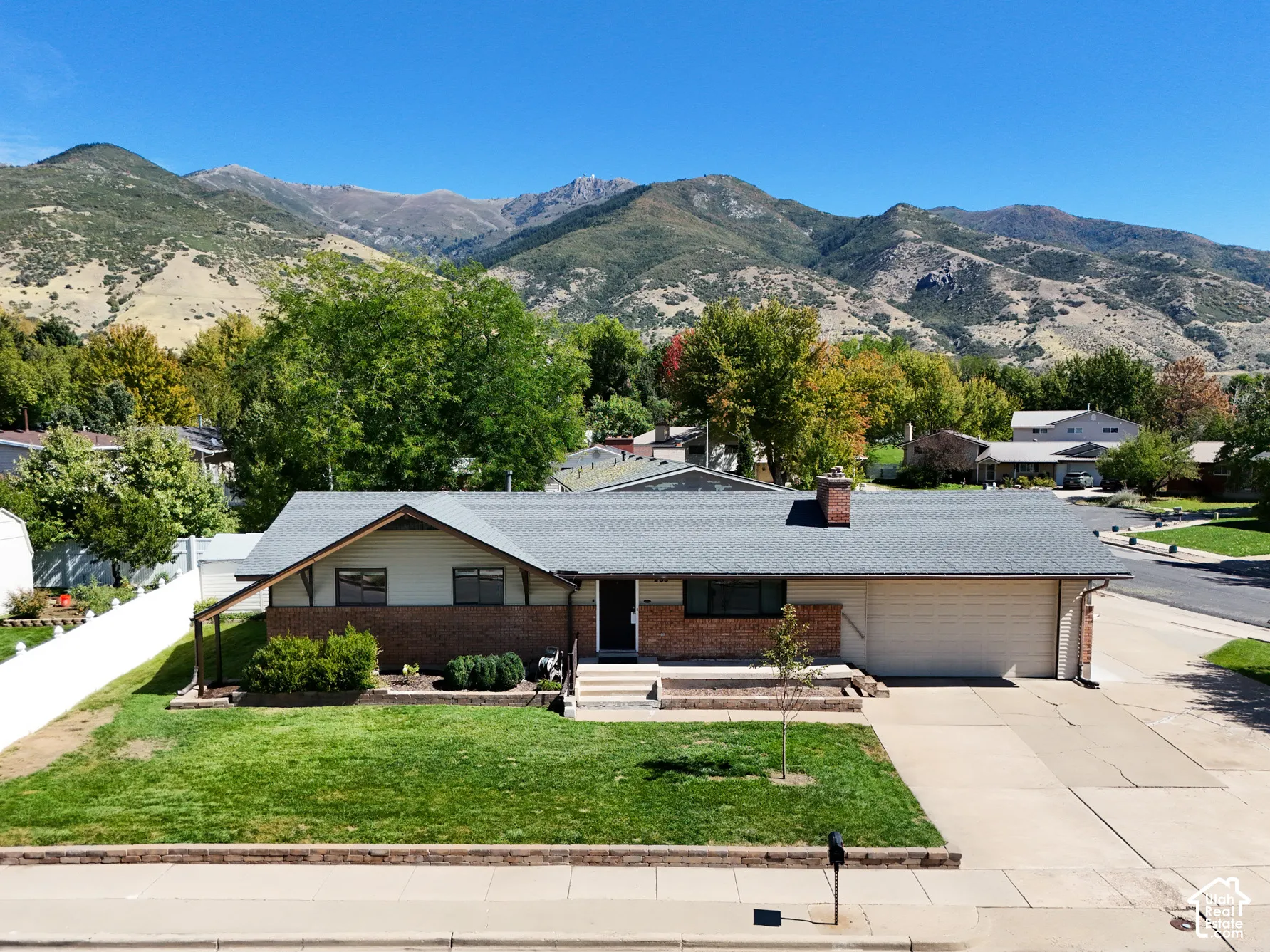 Ranch-style residence featuring a brick facade and an attached two-car garage with mountain in the back.