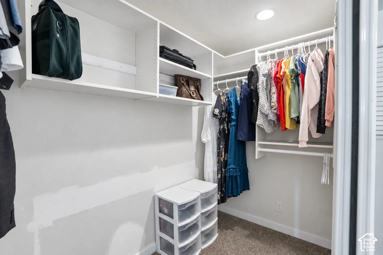 Built-in closet system featuring white shelving, multiple hanging rods, and recessed lighting