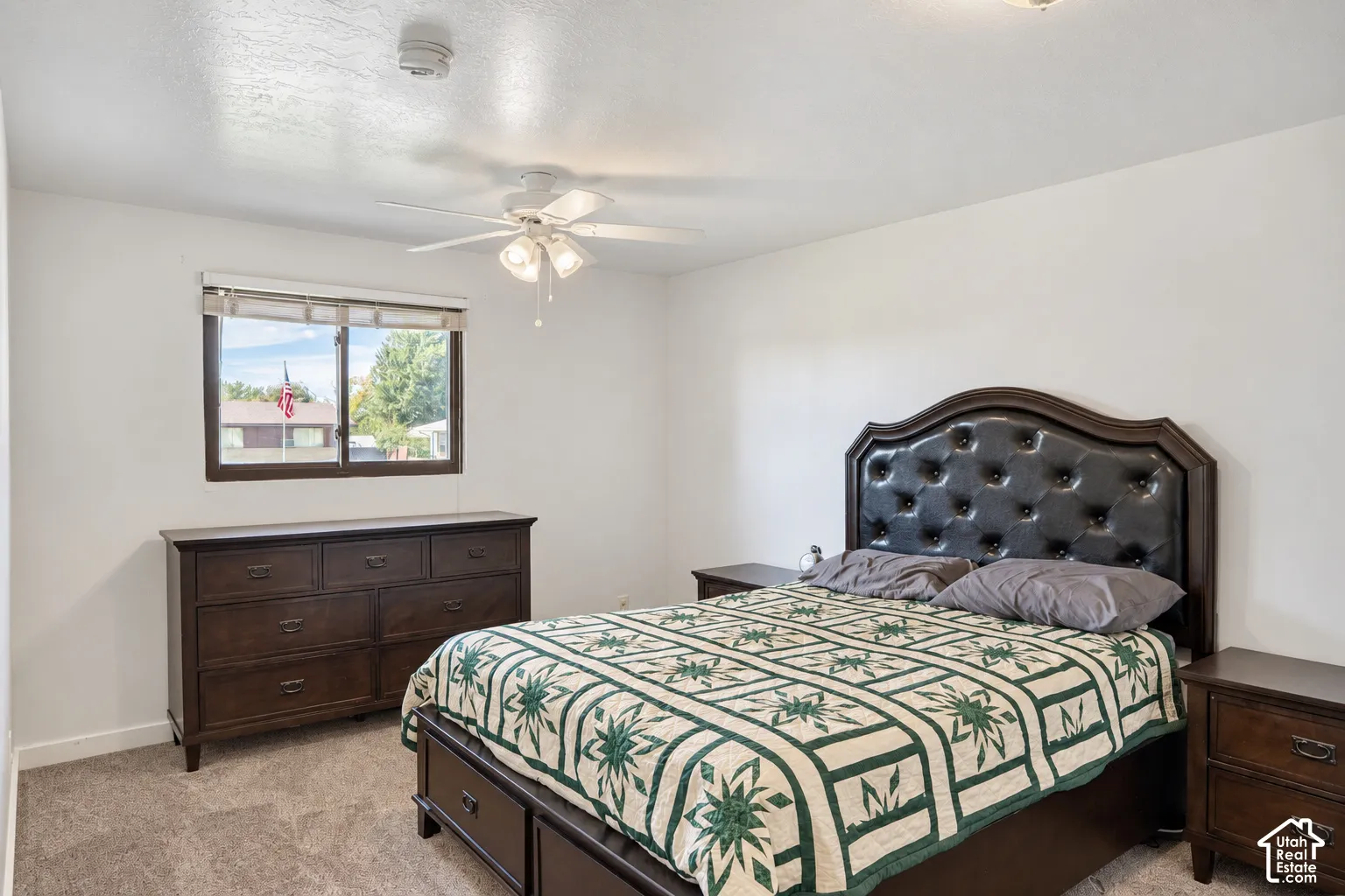 Carpeted flooring, a window with dark wood trim, and a ceiling fan with integrated lighting