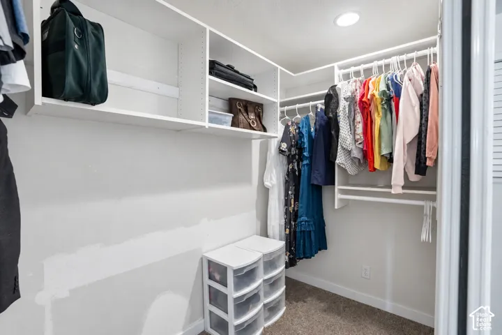 Built-in closet system featuring white shelving, multiple hanging rods, and recessed lighting