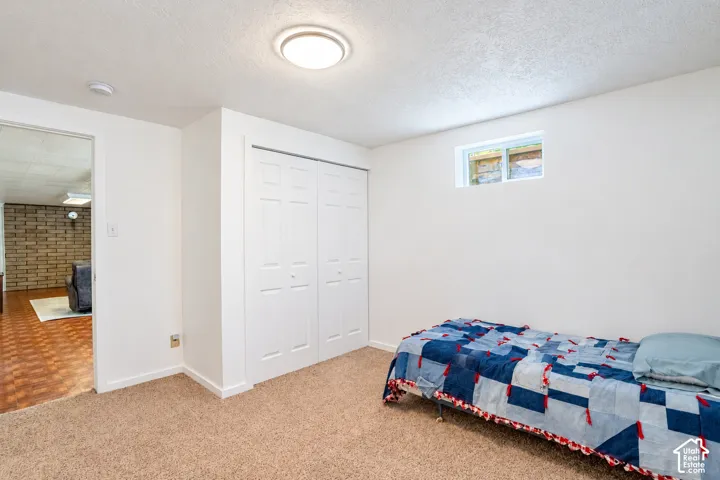 Plush carpet flooring, white painted walls, a flush-mount ceiling light fixture, bi-fold closet doors, and a small window