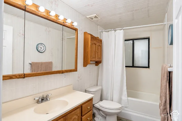 Vanity with integrated sink, wood-finish cabinetry, and overhead bar lighting